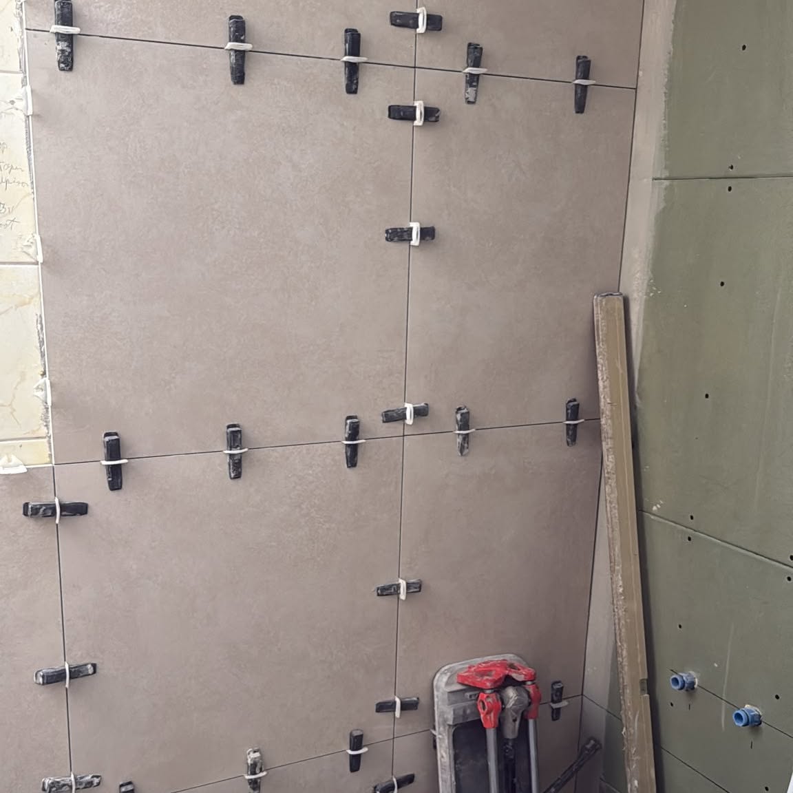 Betegelde wand met levelsysteem, naast groene gipsplaat voor de vochtige ruimte