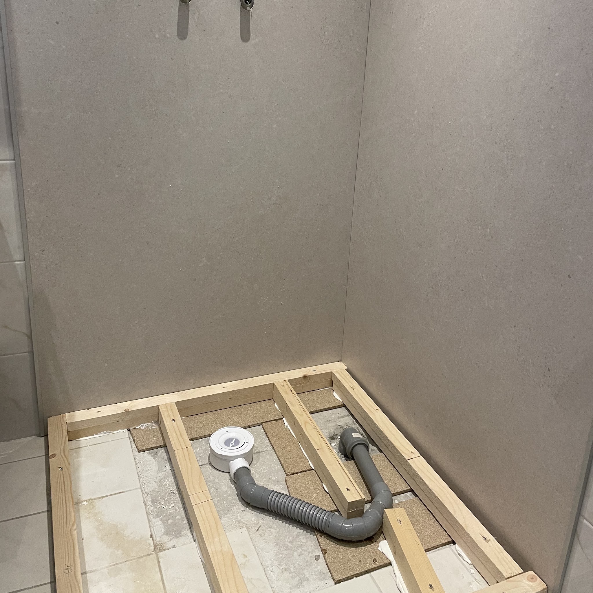 Doucheruimte met een houten opbouw en afvoer voor de nieuwe douchevloer